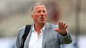 Sir Ian Botham reaches out with his left hand.