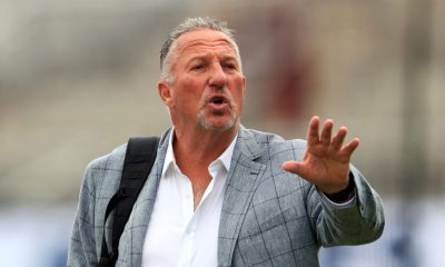 Sir Ian Botham reaches out with his left hand.